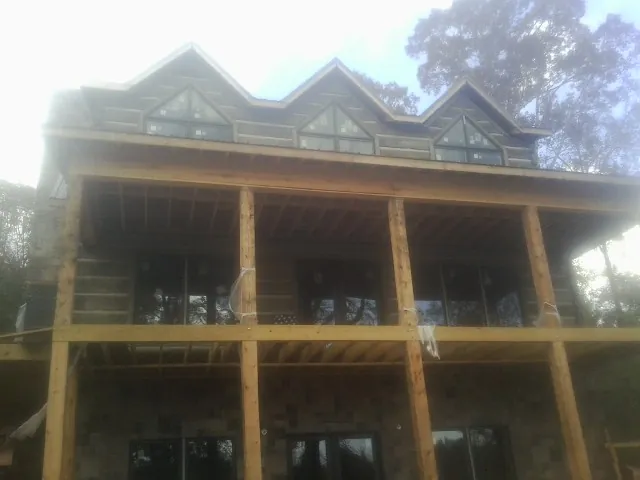 Dormers and porch framing on a large log home under construction — Roof Coating work by our crew in Hamburg